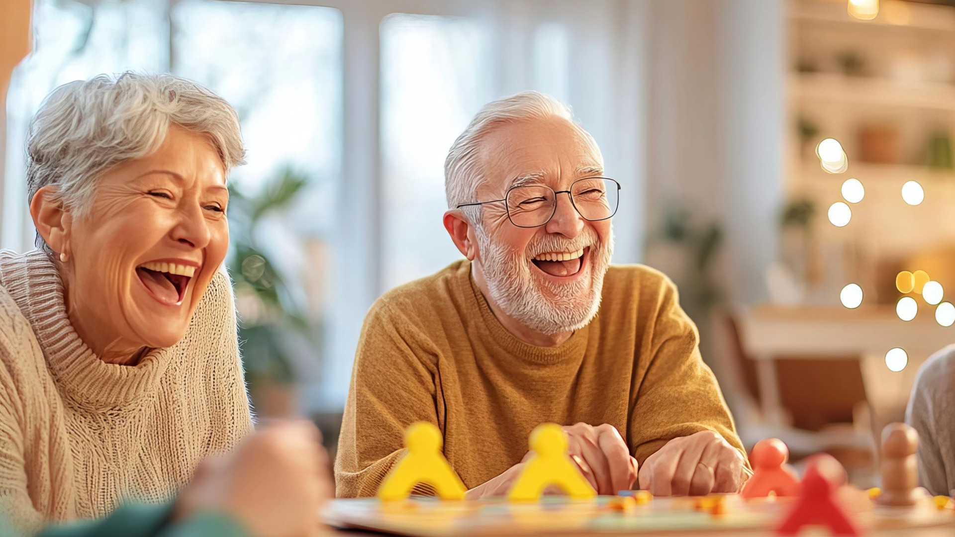 Zwei ältere Menschen spielen ein Brettspiel und lachen vor Freude