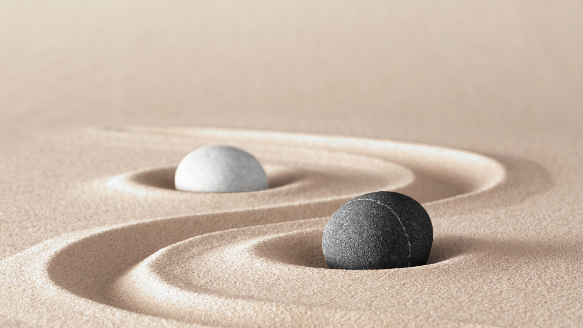 Zwei Steine im Sand versinnbildlichen das Yin und Yang