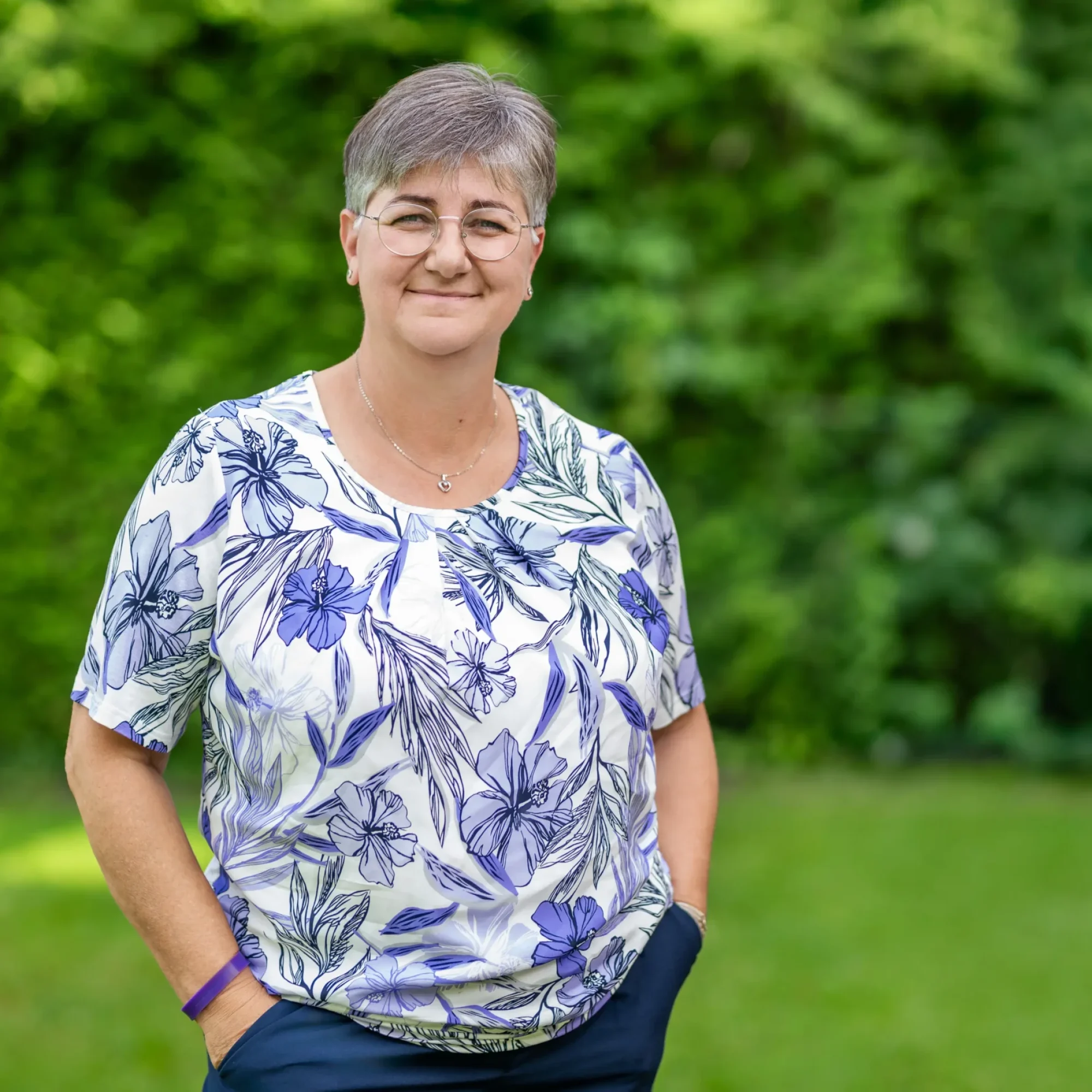 Eva Maria Hofstätter, Expertin für Potenzial- & Kommunikationsmentoring DigiFit 60+, Geragogik-Training & Prana-Anwendungen, steht in der grünen Natur und lächelt zufrieden in die Kamera