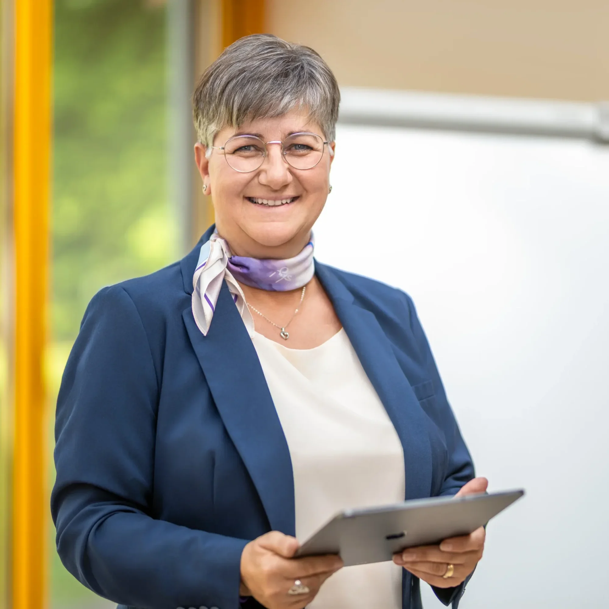 Eva Maria Hofstätter bei der Arbeit als Expertin für Potenzial- & Kommunikationsmentoring DigiFit 60+, Geragogik-Training & Prana-Anwendungen. Sie steht vor einem Flipchart und hält ein Tablet in der Hand.
